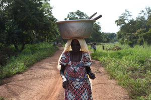 Mujer beneficiaria de un proyecto en Benin, llevando un barreño de agua. 