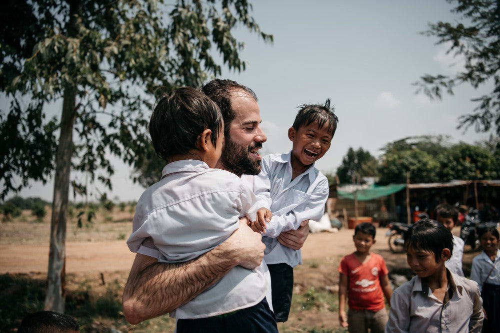Pablo Urbano, fundador de AUARA cogiendo en brazos a dos niños en un proyecto en Camboya