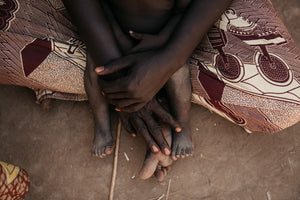 Manos y pies entrelazados de una madre y un niño del Chad