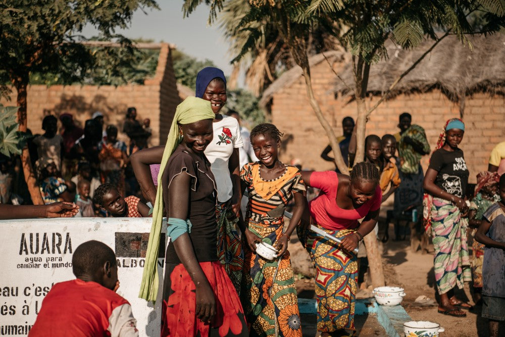 Mujeres sonriendo en un pozo de un proyecto de AUARA, alrededor de mucha gente