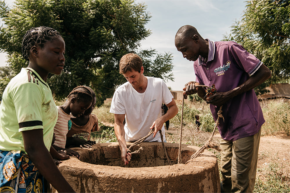 Voluntario sacando agua del pozo junto a un grupo de personas