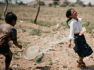 Niños sonriendo en un pozo construido en Camboya por AUARA